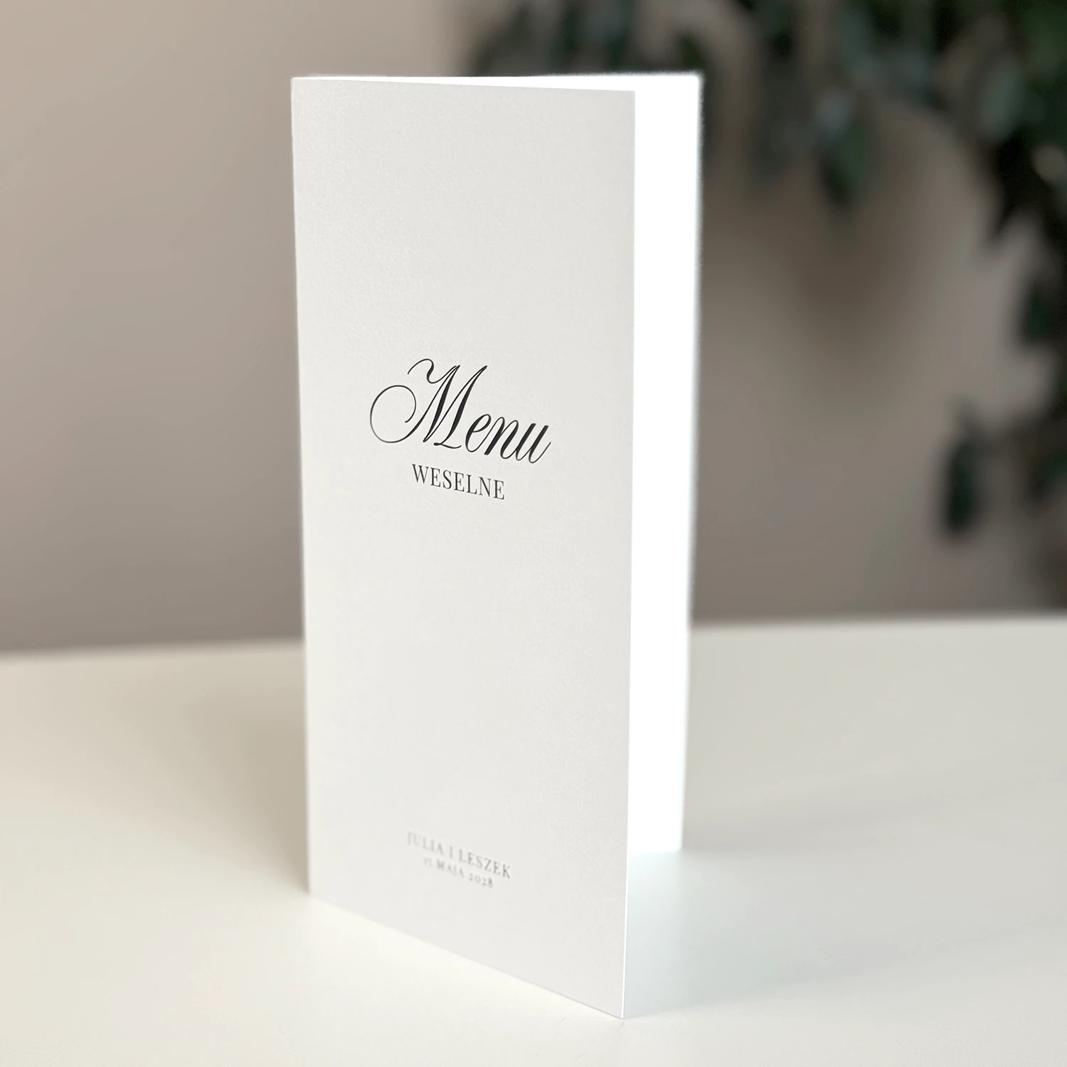 Otwierane menu z harmonogramem wesela na śmietankowym papierze z eleganckim czarnym drukiem.