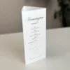 Stojące menu z harmonogramem wesela w formie trójkąta, z widoczną ścianką z planem przyjęcia.